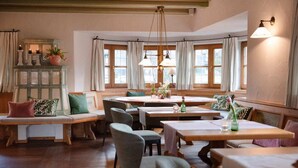 A cozy dining area with wooden tables and chairs, a bench, and a decorative cabinet. - Landhaus Christl am See (Bad Wiessee)