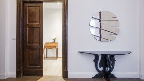Ein Zimmer mit Holztür, rundem Spiegel und Tisch mit ungewöhnlichem Fuß.
