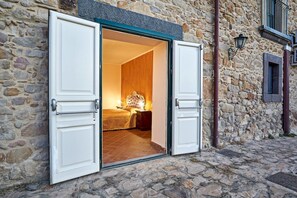 Ein Steinhaus mit einem Hauseingang, der ein Bett und einen Nachttisch zeigt.
