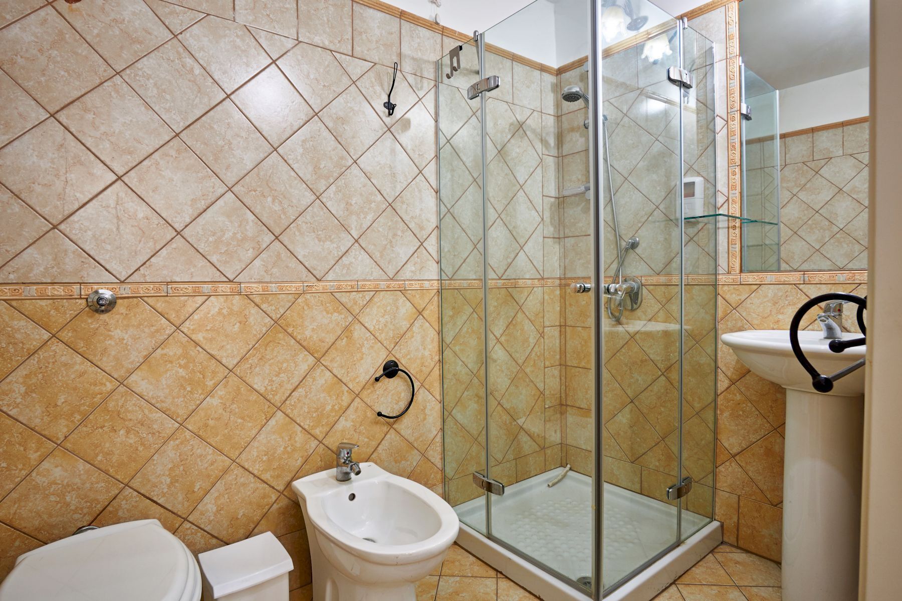 A bathroom with a glass-enclosed shower, a bidet, and a sink.