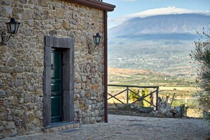 A stone building with a green door and two wall-mounted lanterns. - Agriturismo Conte Ruggero (Regalbuto)