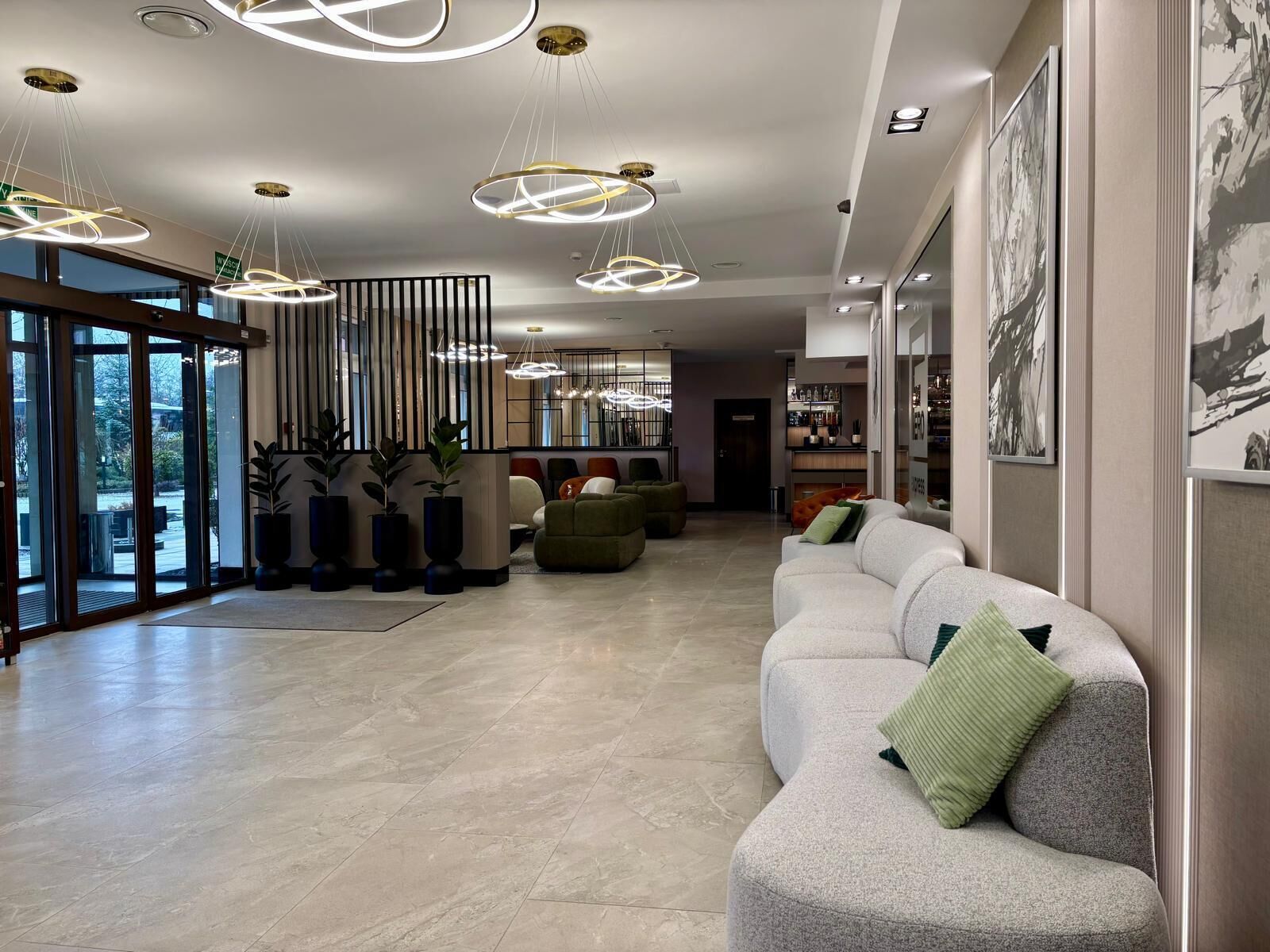 A modern lobby with a seating area, large windows, and contemporary lighting fixtures.