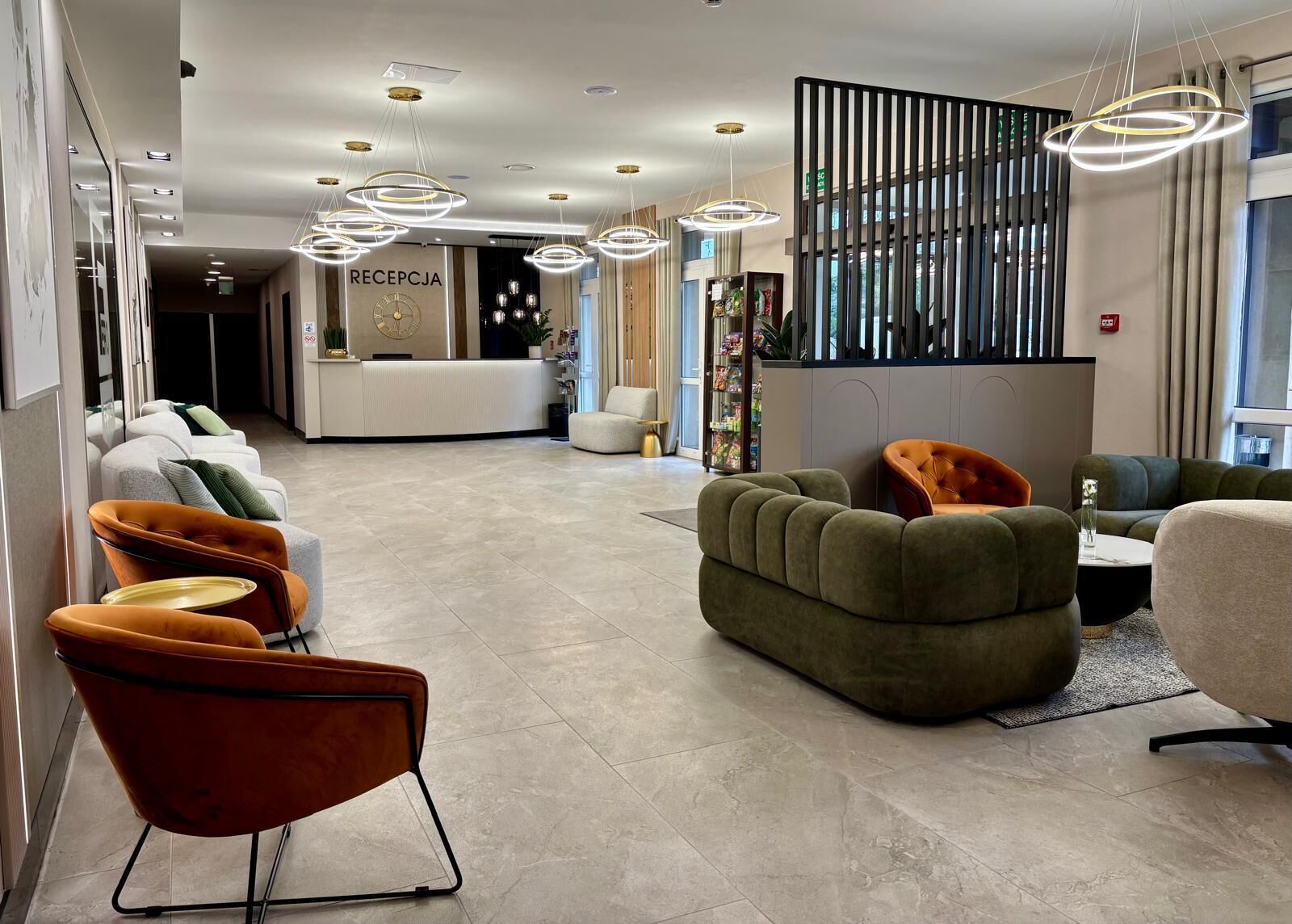 A modern hotel lobby with a reception desk, seating area, and decorative lighting.