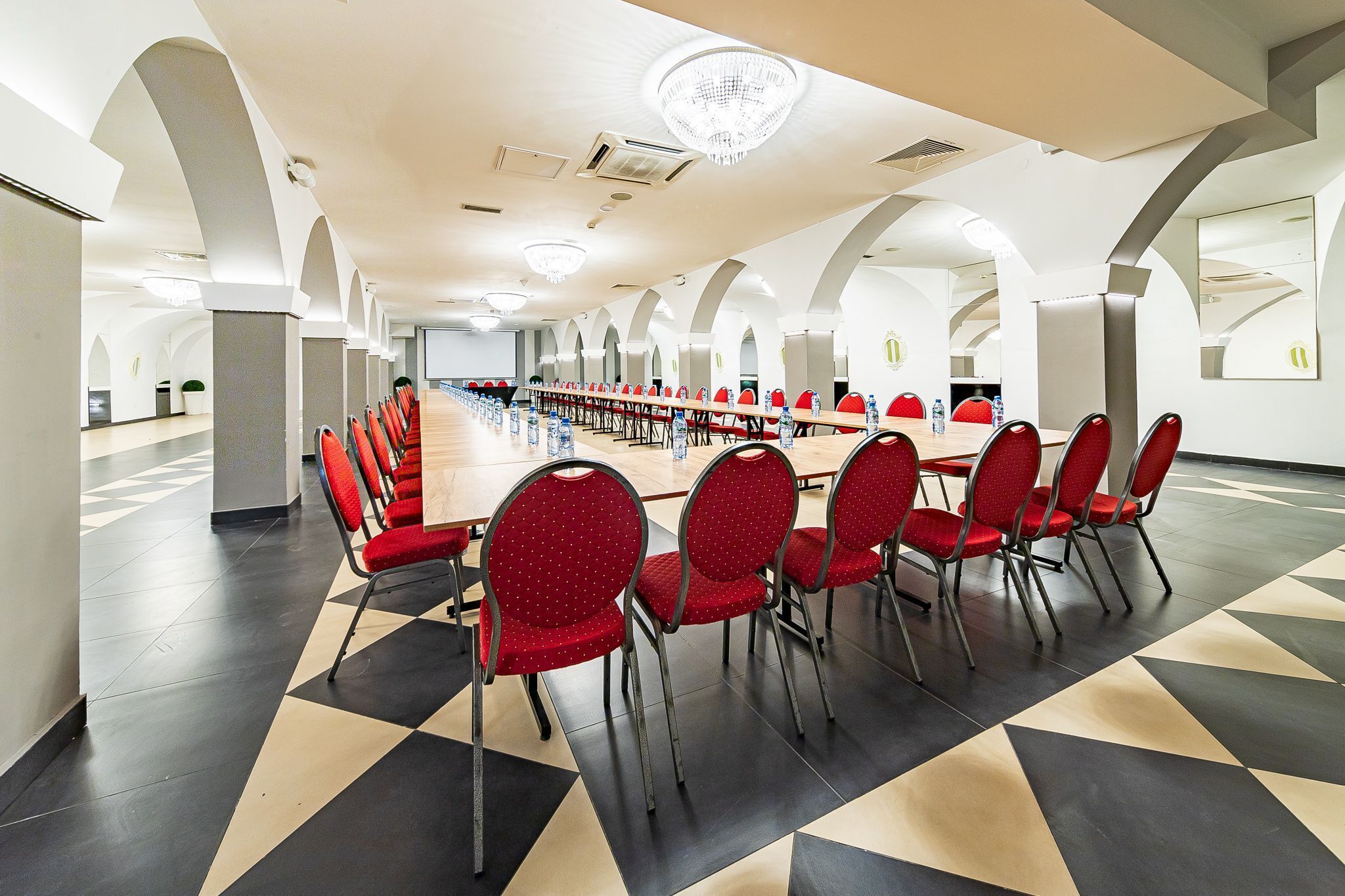 A conference room with a long table, red chairs, and a geometric patterned floor.
