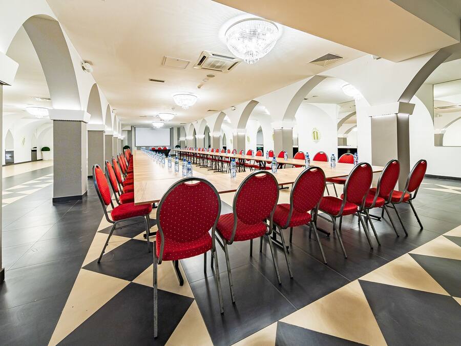 A conference room with a long table, red chairs, and a geometric patterned floor.