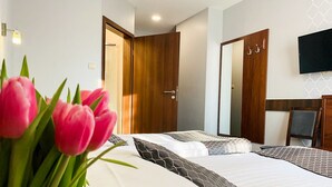 A hotel room with a bed, a wooden door, a mirror, and a flat-screen TV. - Hotel Fero Express (Kraków)