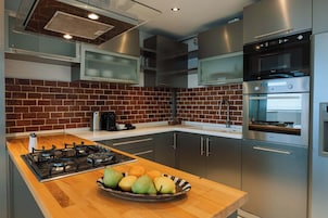 Una cocina moderna con estufa a gas, electrodomésticos de acero inoxidable y salpicadero de ladrillo.