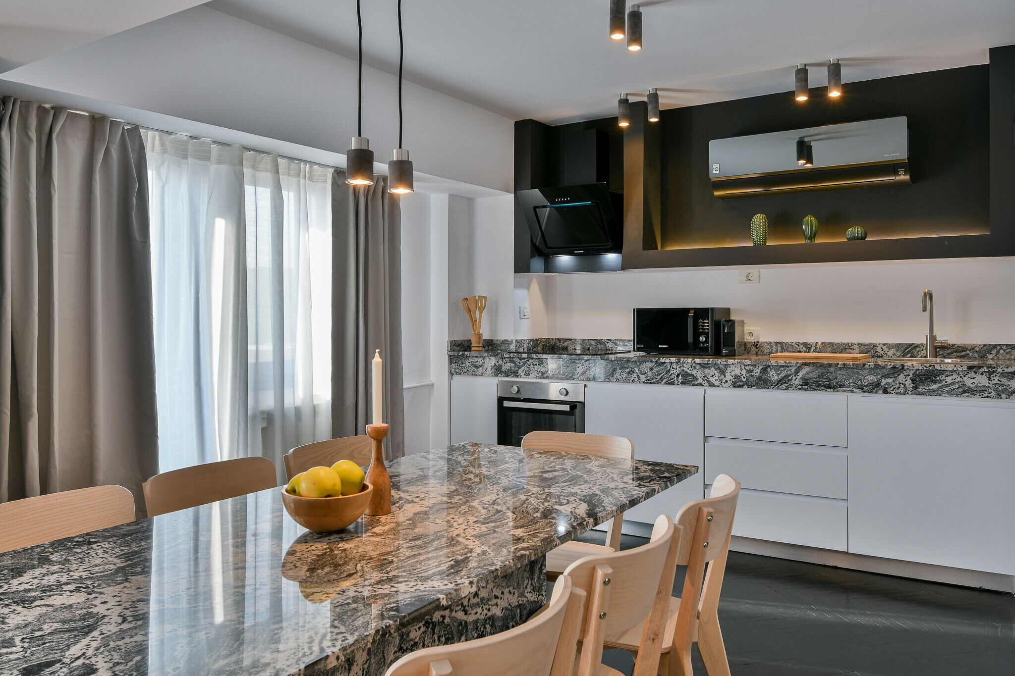Cozinha moderna com bancada de granito, eletrodomésticos embutidos e iluminação pendente.