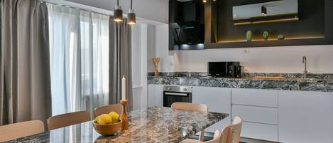 Cozinha moderna com bancada de granito, eletrodomésticos embutidos e iluminação pendente.