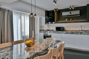 A modern kitchen with a granite countertop, built-in appliances, and pendant lighting.