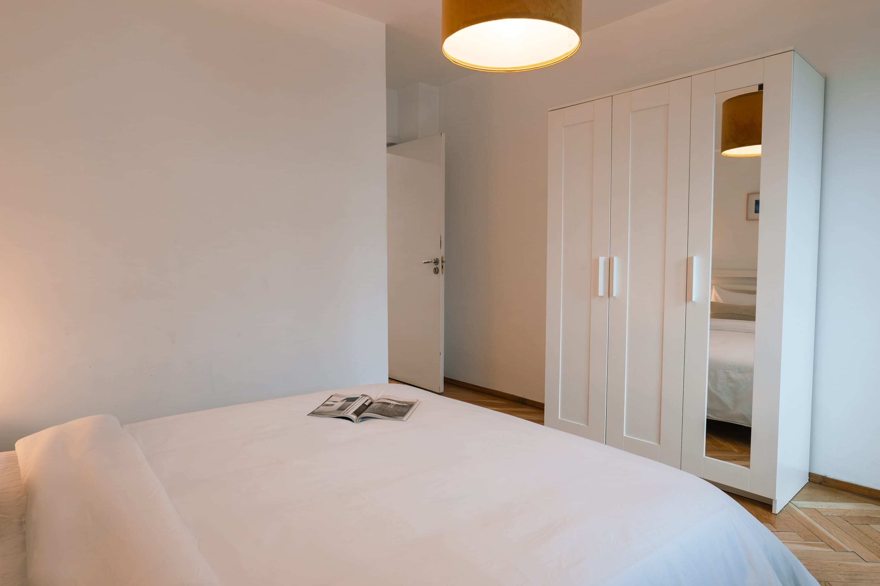 A bedroom with a bed, a wardrobe, and a door leading to another room.