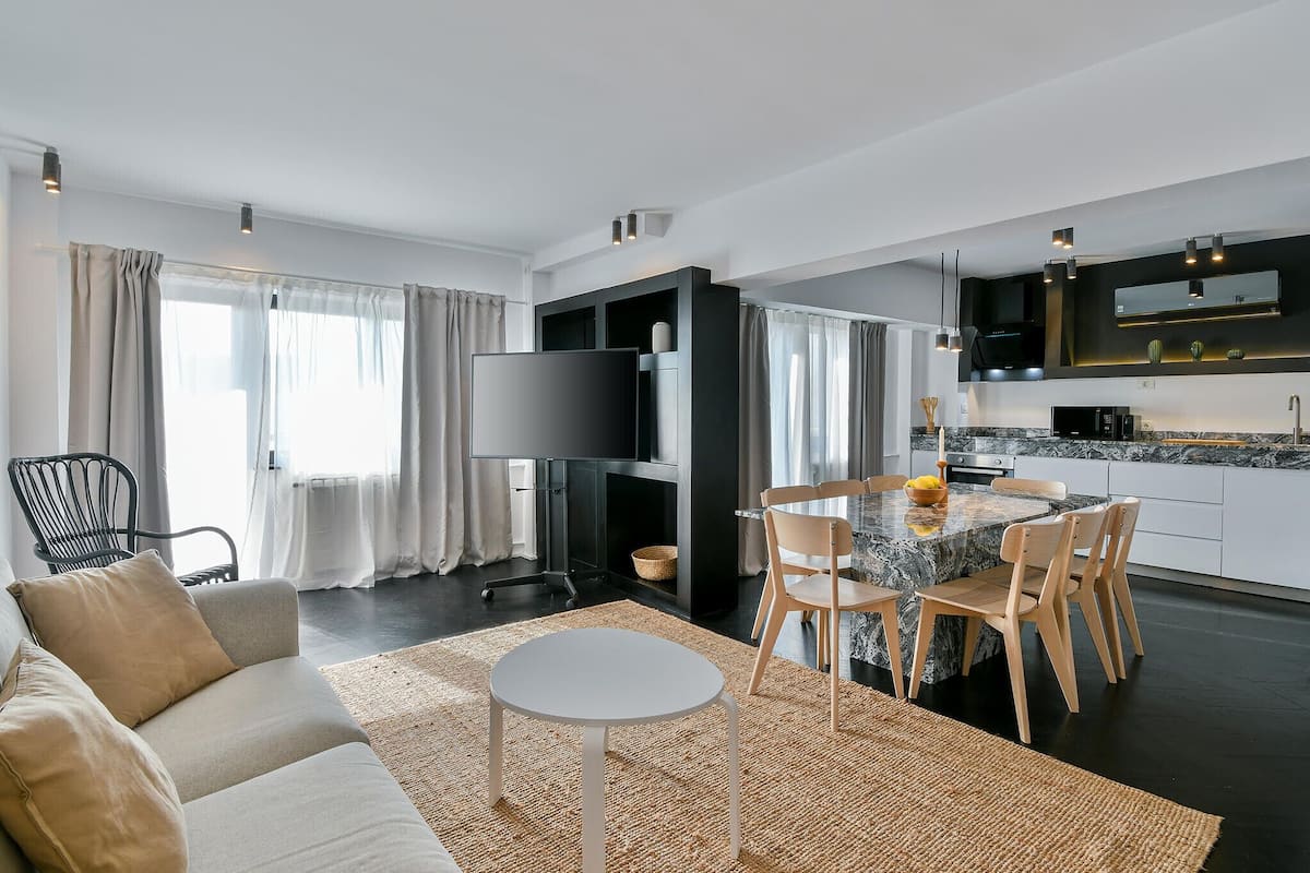 A modern living room with a sofa, a round table, and a TV.