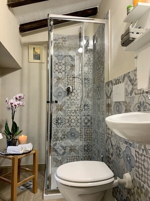 Een badkamer met een douche, toilet, wastafel en decoratieve tegels.