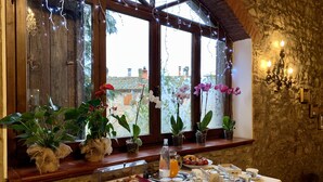 A breakfast setup with food items, a table, and potted plants near a window with a view.