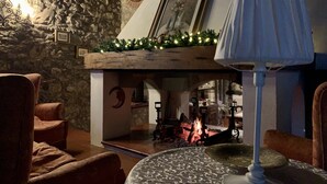 A cozy room with stone walls, a fireplace, and a table with a patterned tablecloth.