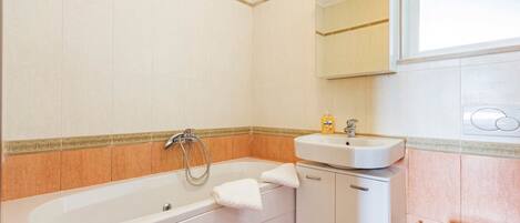 Et badeværelse med badekar, vask og spejl.