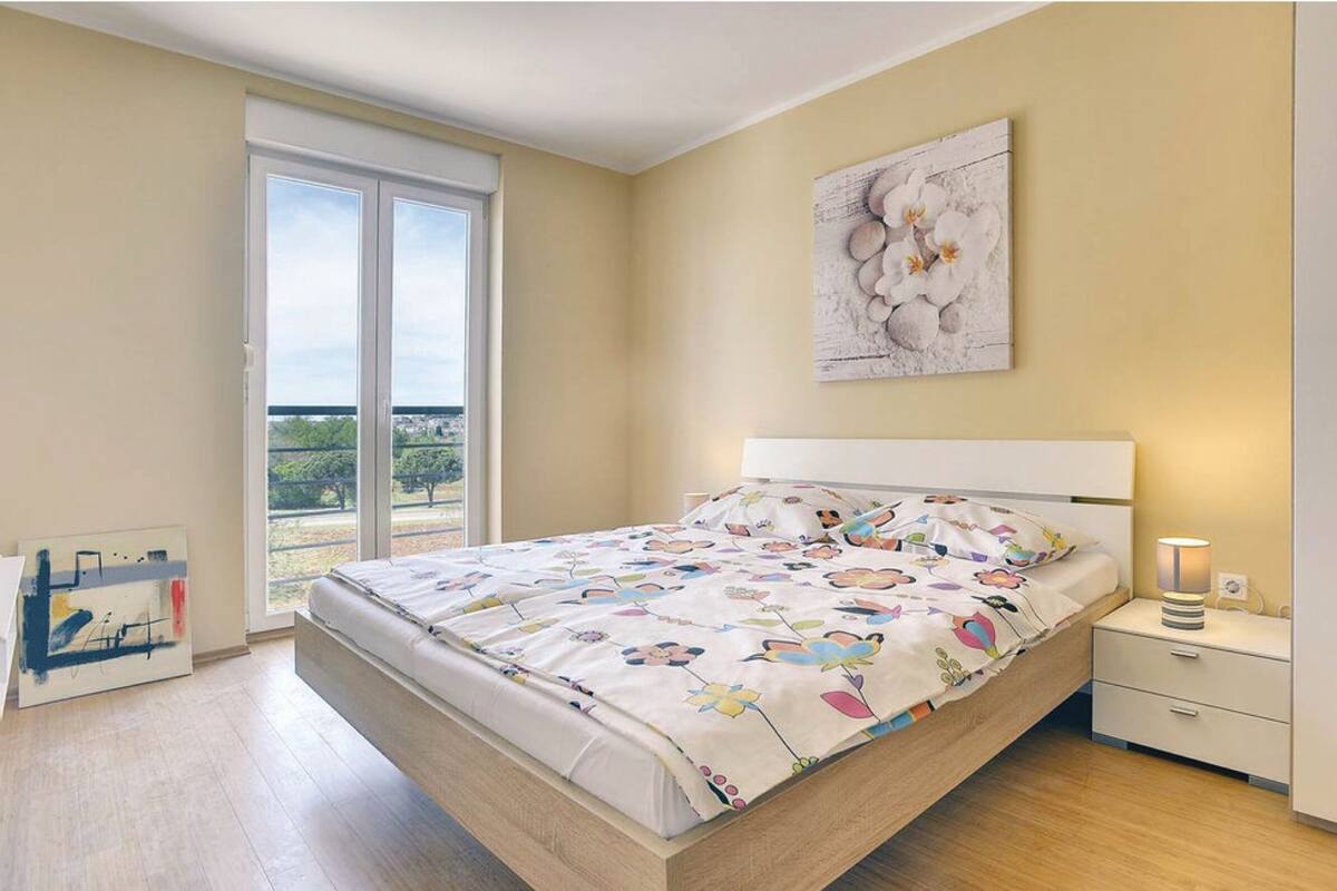 A bedroom with a bed, a nightstand, a lamp, and a painting on the wall.