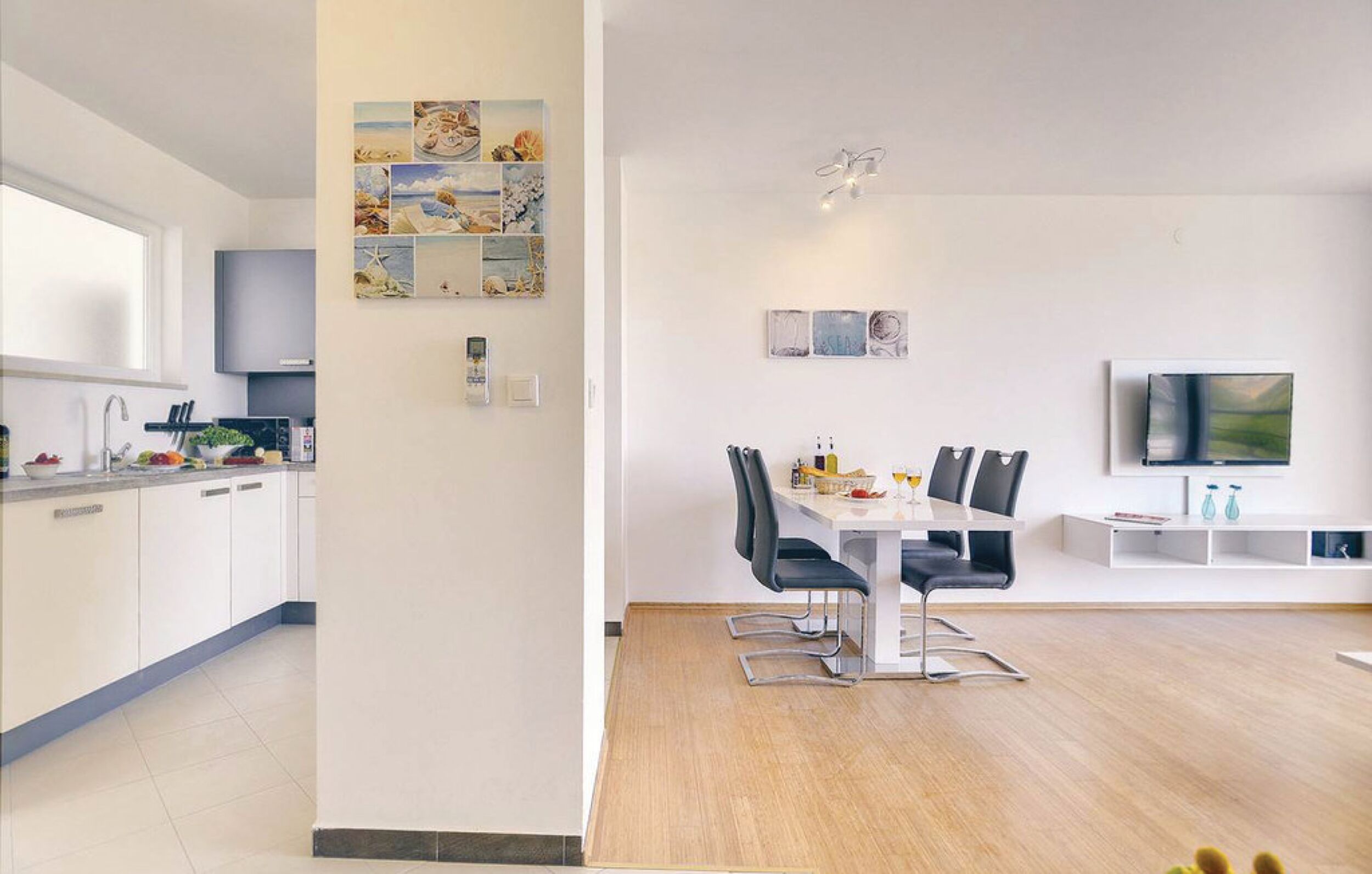 Een moderne keuken met witte kastjes en een eethoek met een tafel en stoelen.