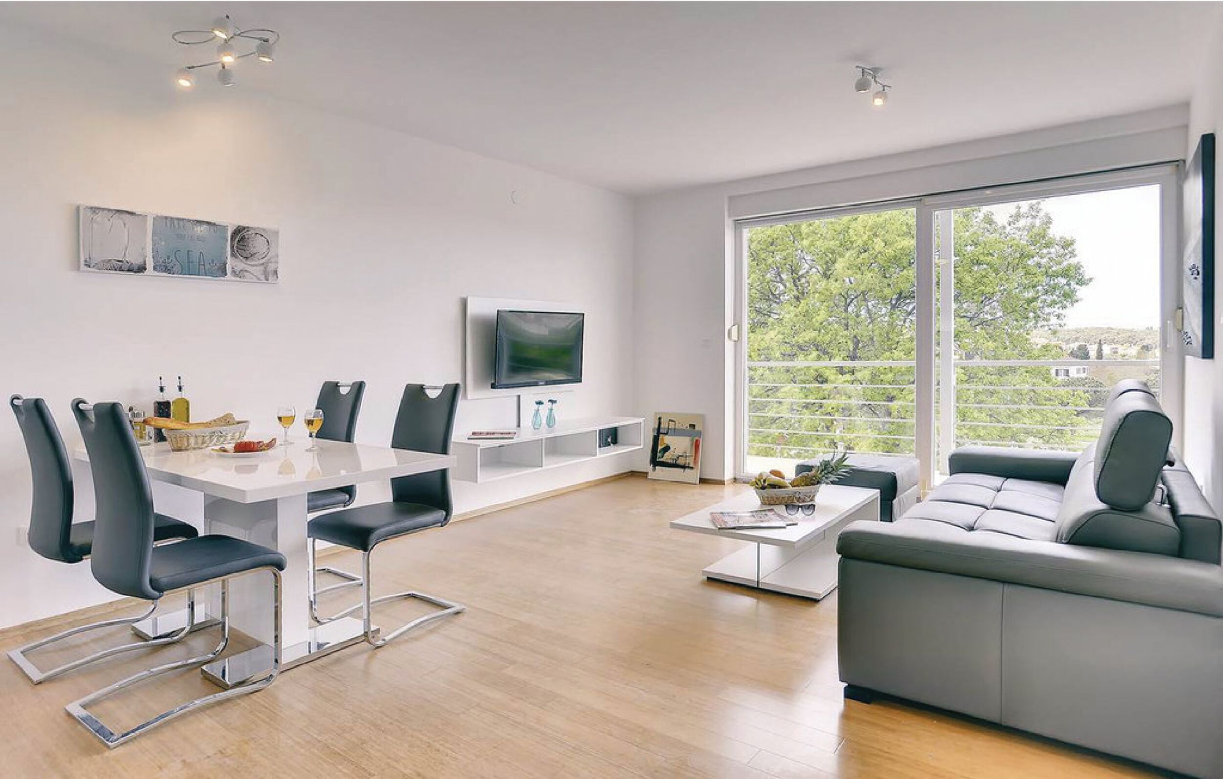 Un salon moderne comprenant un coin repas, un canapé et un téléviseur fixé au mur.