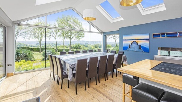 A spacious dining area with a large table and chairs, skylights, and a view of the outdoors. - A large  group retreat that sleeps 16 guests  in 4 bedrooms (Chew Stoke)