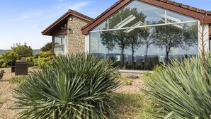 A modern house with a stone facade, large glass windows, and a view of the surrounding landscape. - A large  group retreat that sleeps 16 guests  in 4 bedrooms (Chew Stoke)