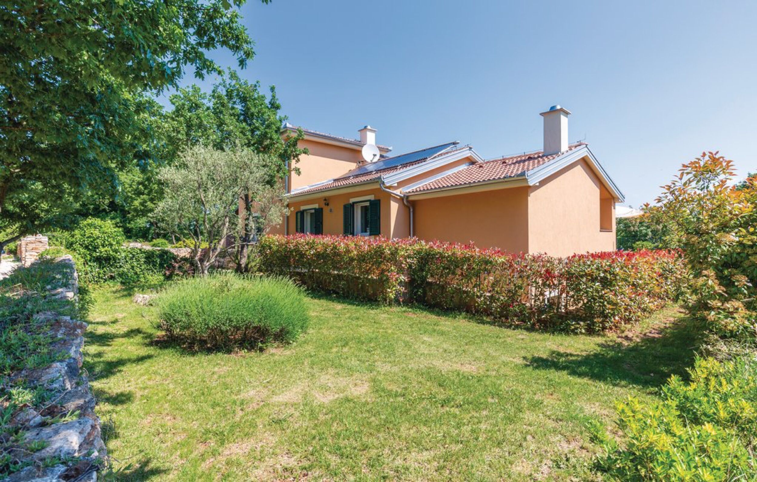 Una casa con jardín, antena parabólica visible y chimenea.