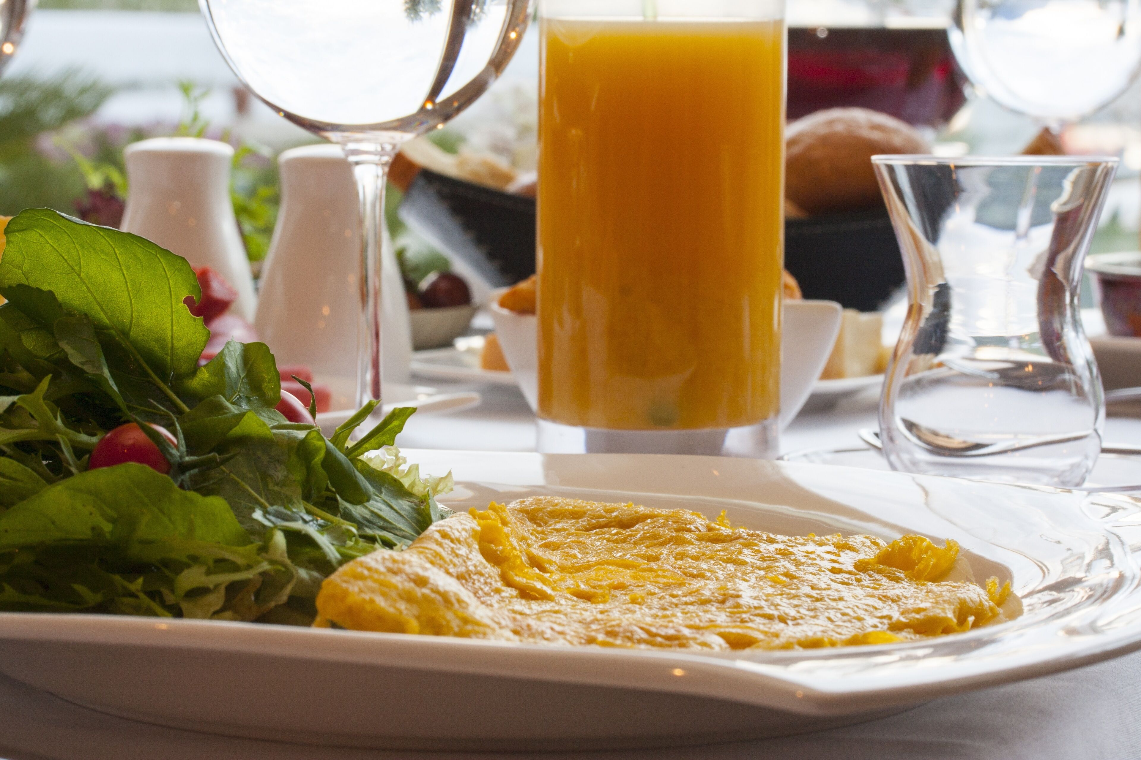 A breakfast setting with a plate of eggs, a glass of orange juice, and a salad.