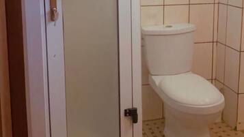 Un baño con inodoro, cabina de ducha y paredes con azulejos.