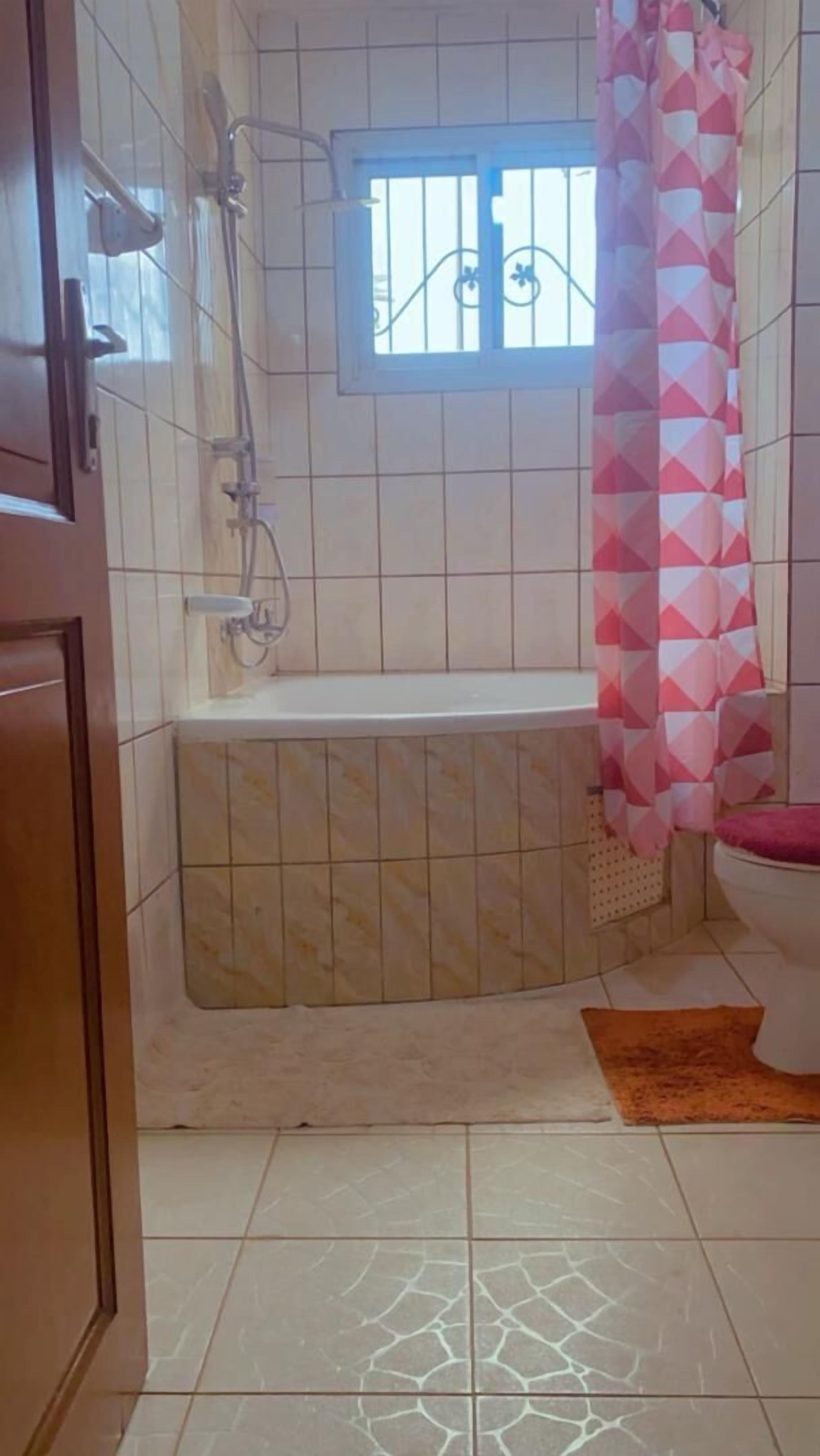 Un baño con bañera, ventana y retrete.