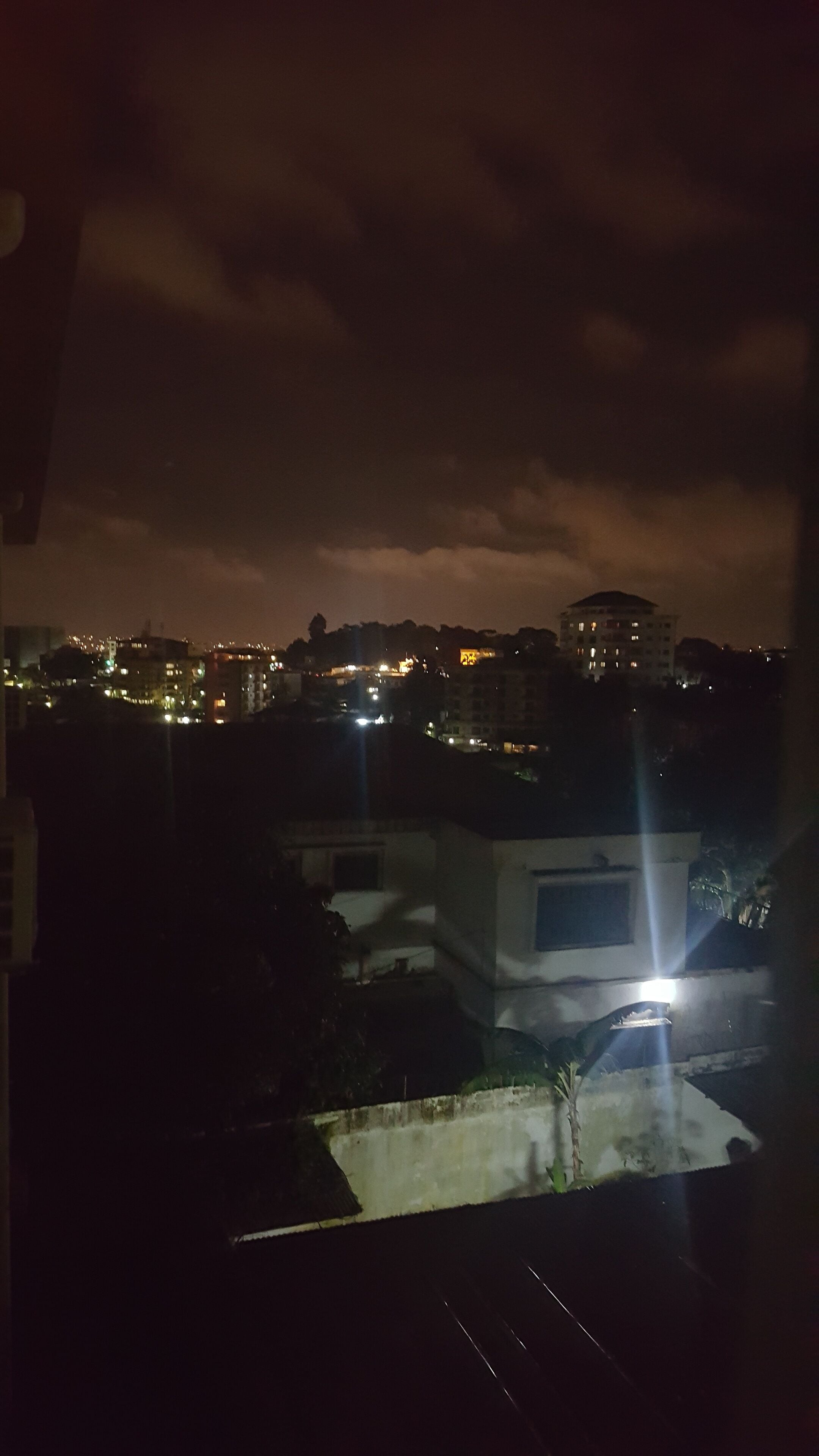 A nighttime cityscape with buildings and streetlights.