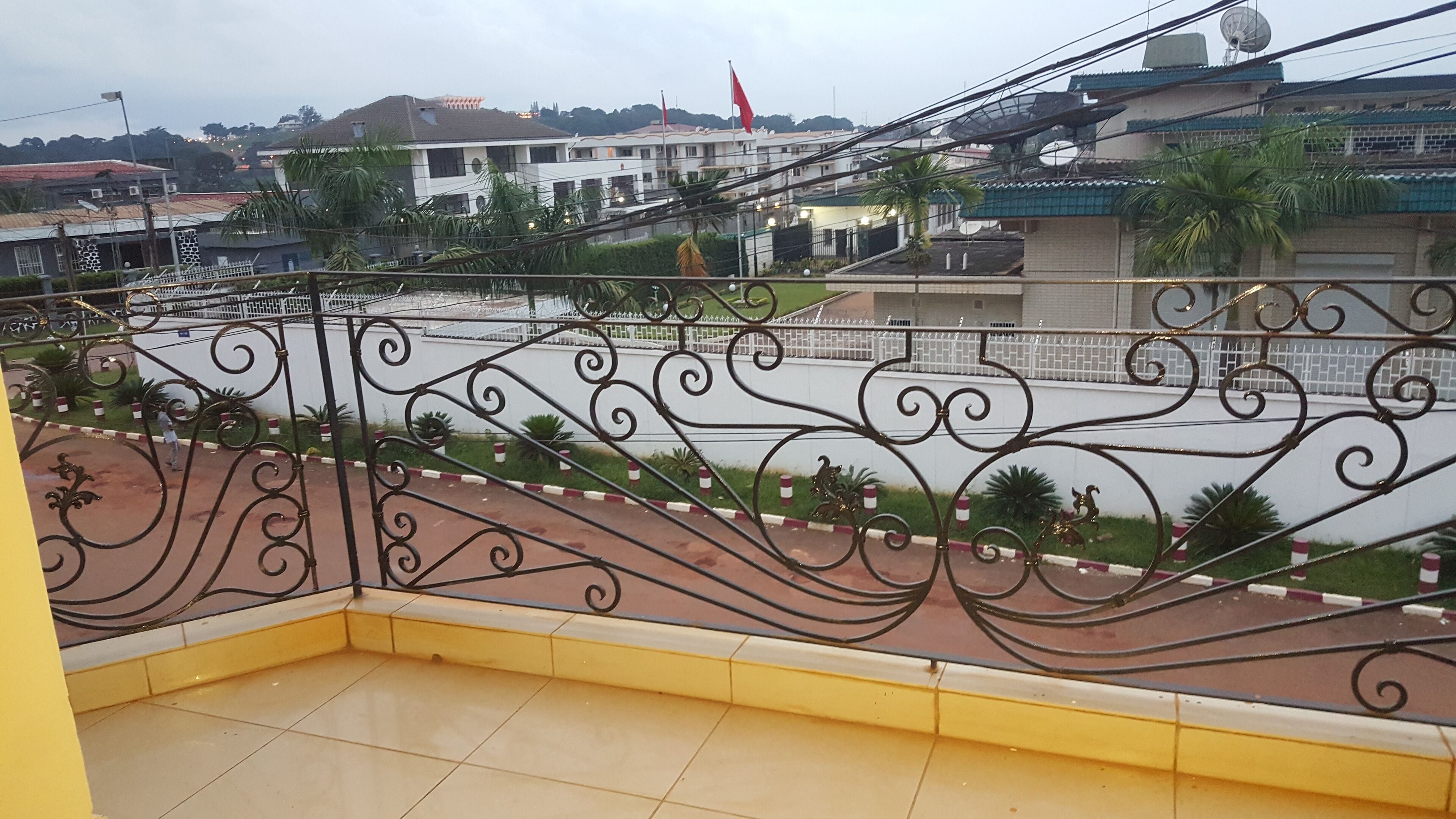 A balcony with a yellow floor and black wrought iron railing.