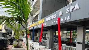 A building with a sign for 'Emile Suites & SPA' and outdoor seating with tables and chairs. - Résidences hôtelières Micheline et Emile, Bastos (Yaoundé)