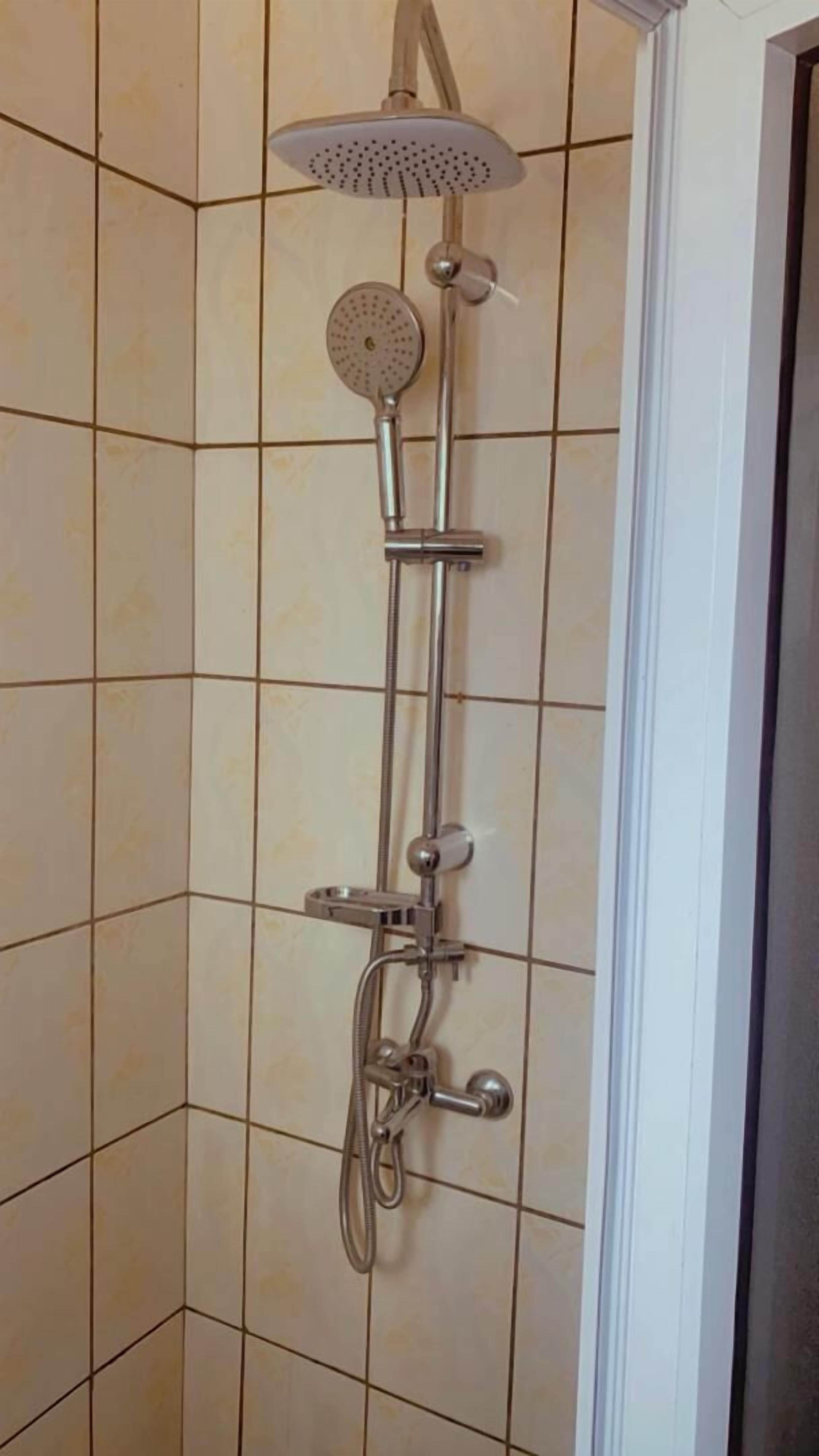 A shower with a handheld showerhead, a wall-mounted showerhead, and a handheld shower nozzle.