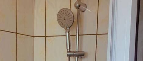 A shower with a handheld showerhead, a wall-mounted showerhead, and a handheld shower nozzle.
