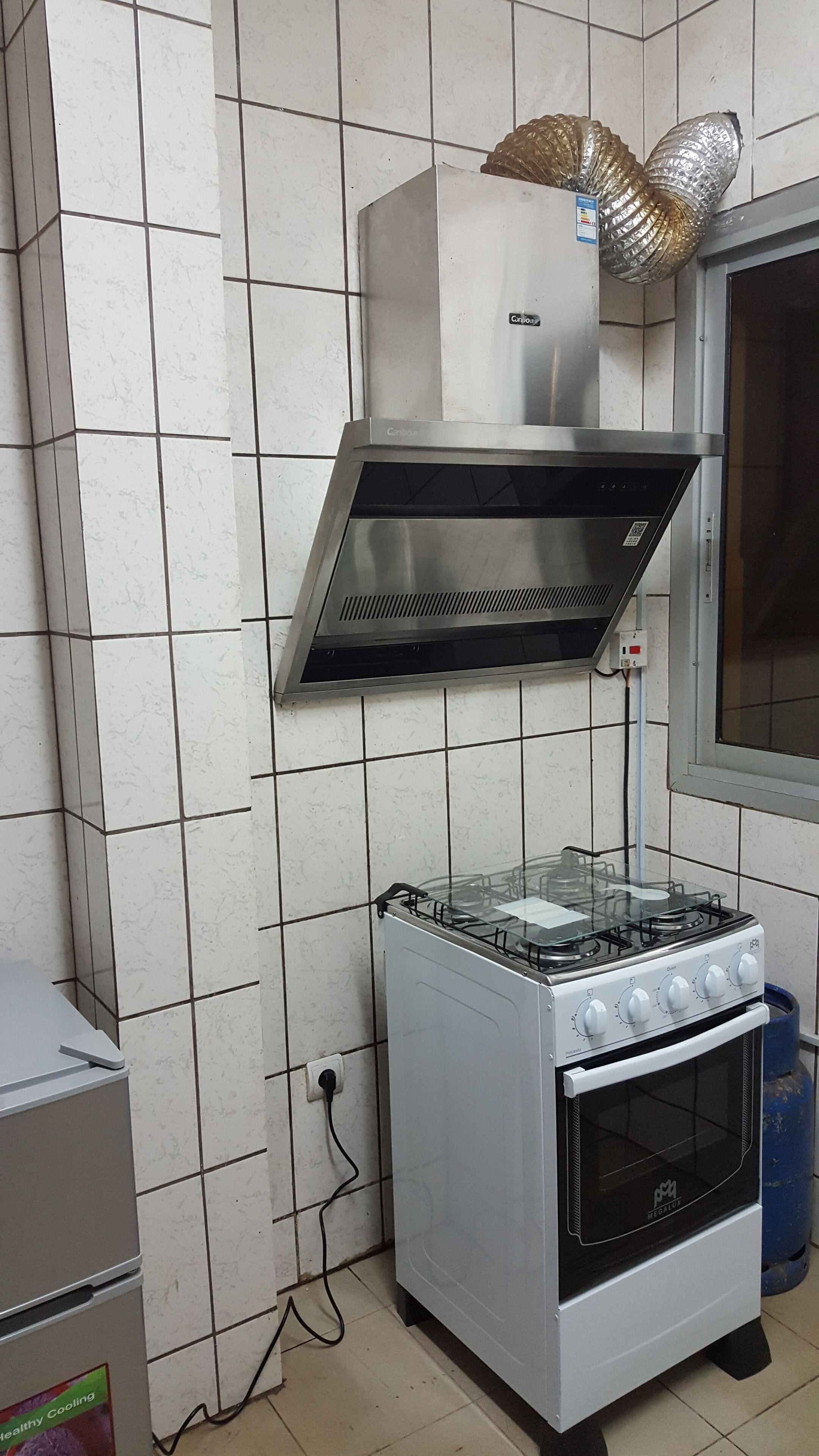 A kitchen with a gas stove, oven, and a range hood above the stove.
