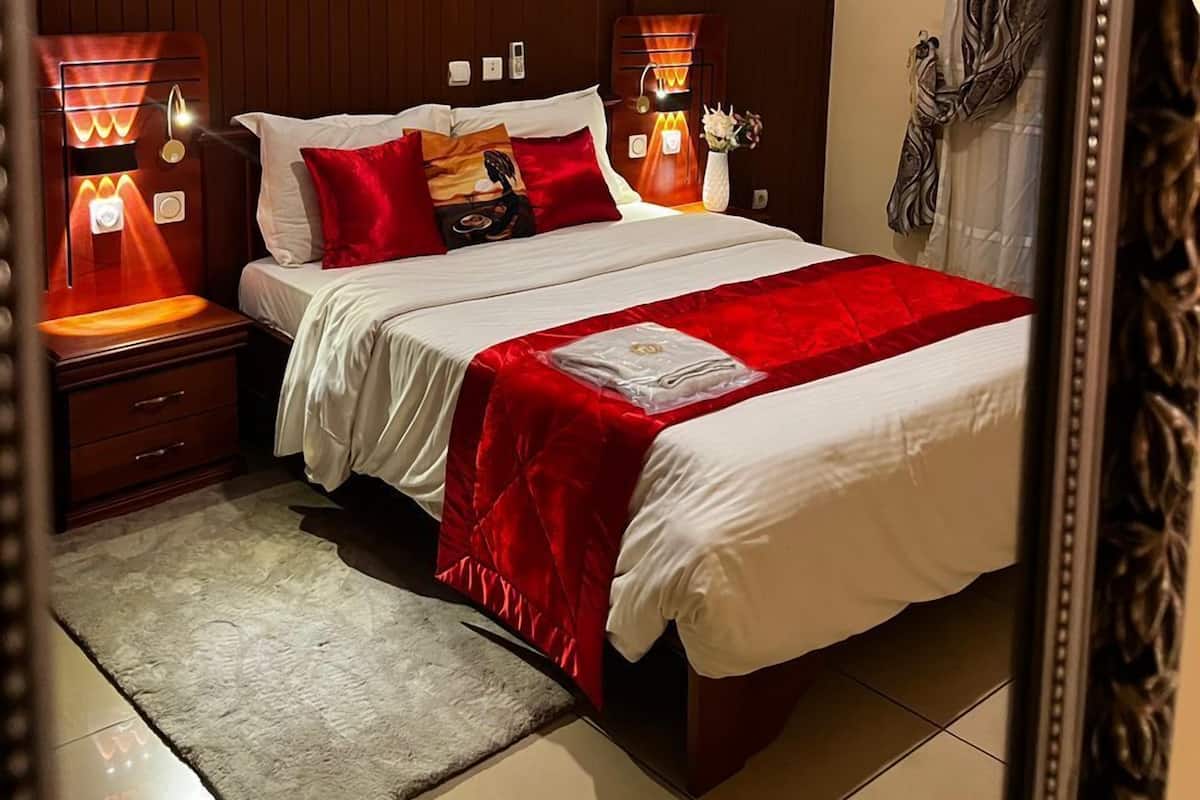 Una habitación de hotel con una cama grande, dos lámparas de noche, una obra de arte en la pared y un espejo.