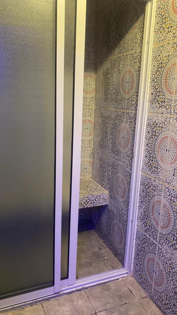 Un baño con zona de ducha que presenta intrincados diseños de azulejos y un banco.
