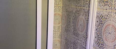 Un baño con zona de ducha que presenta intrincados diseños de azulejos y un banco.