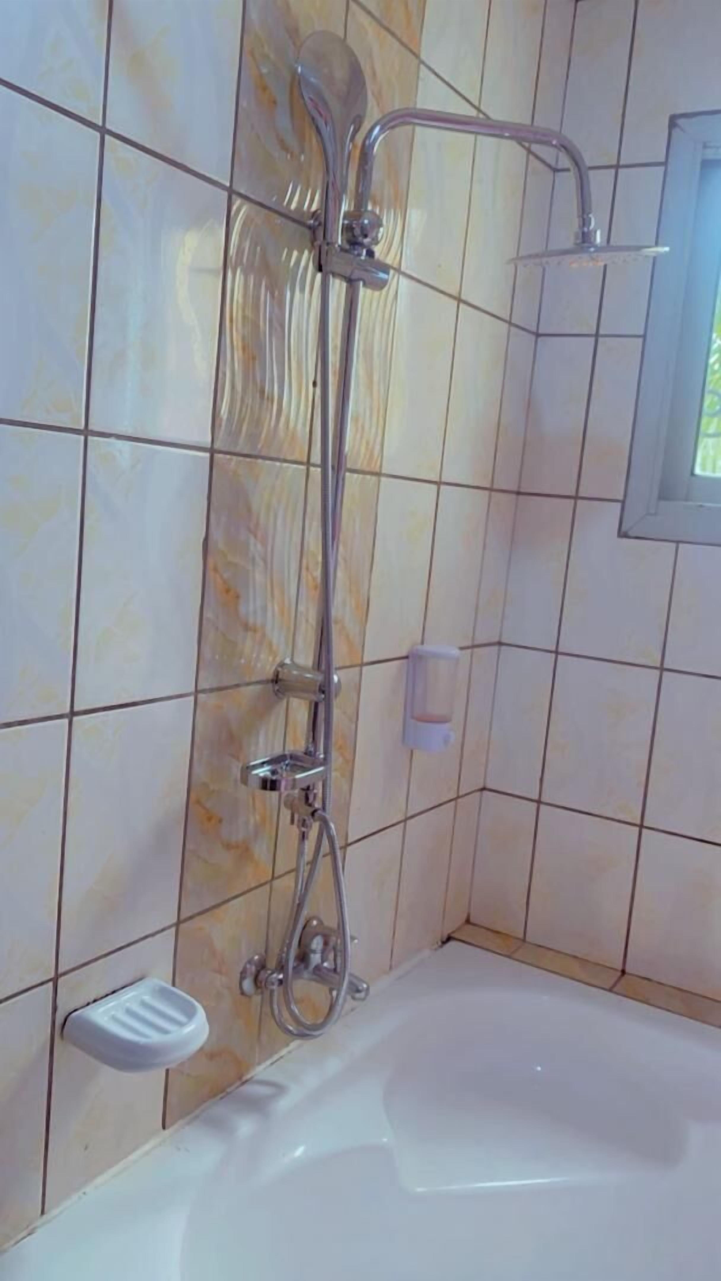 Une salle de bain avec une douche, une baignoire et une fenêtre.