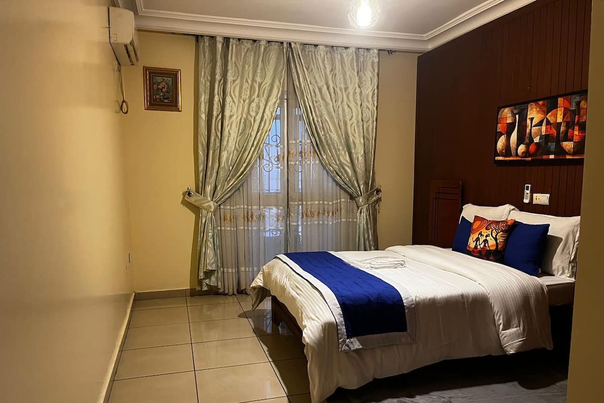 Un dormitorio con una cama, cortinas, un cuadro en la pared y un óleo.