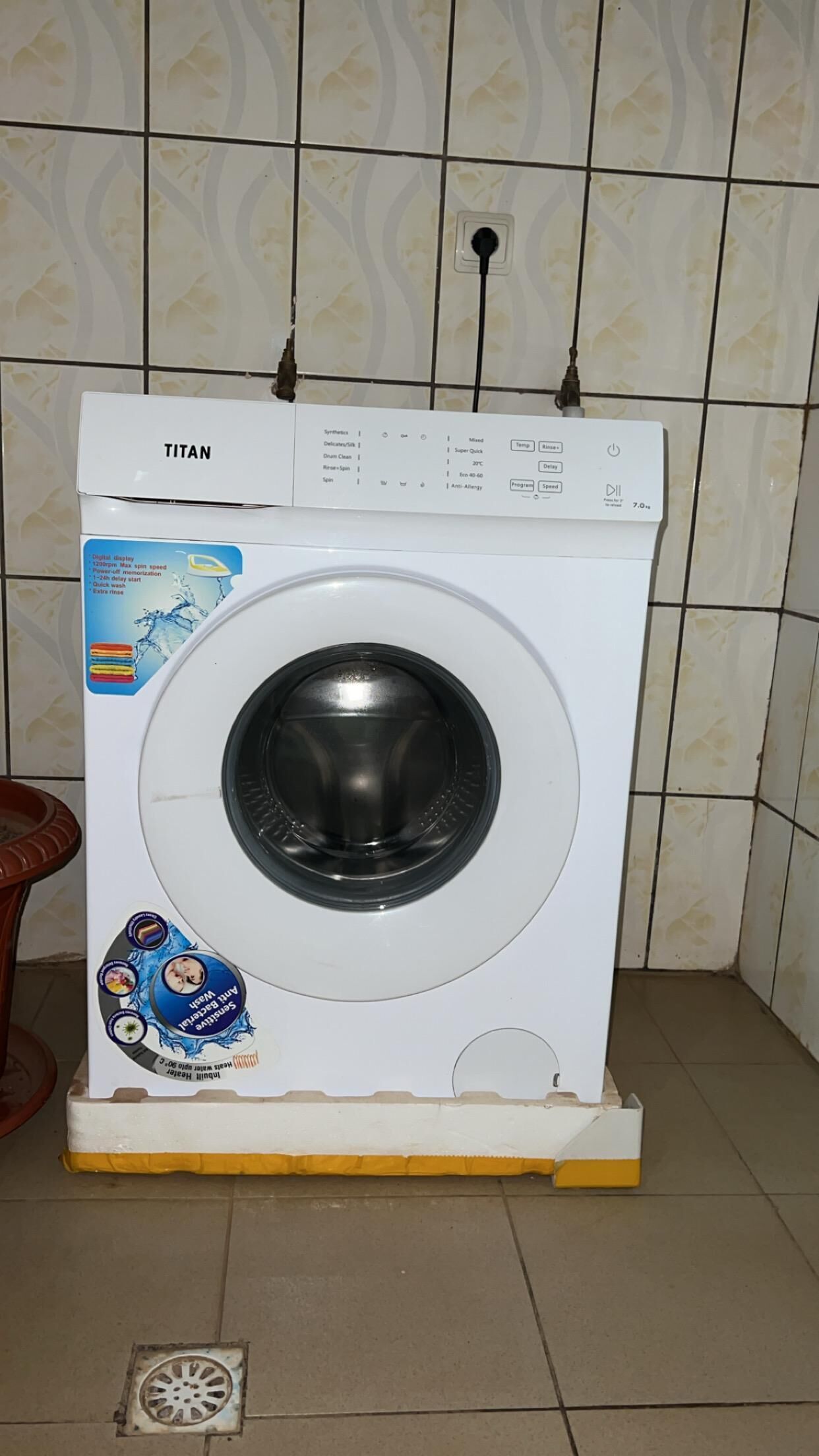 A white washing machine with a control panel, placed on a yellow platform.
