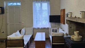 Ein gemütliches Zimmer mit einer Sofagarnitur, einem an der Wand montierten Fernseher und einem Kamin.