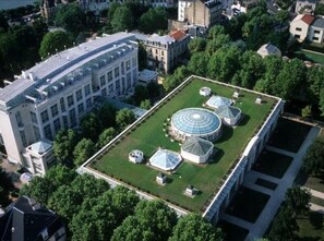 Stunning historic building with a glass facade, surrounded by lush greenery and a central courtyard.