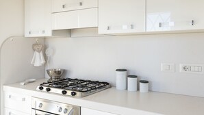 A kitchen with white cabinets, a gas stove, a sink, and a hanging towel. - Villetta has two levels with beautiful sea view and located in front of a small park for children an (Golfo Aranci)