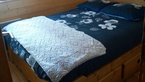 A wooden bed with a floral bedspread and a heart-shaped headboard. - Appartement Plein Centre du Chinaillon (Le Grand-Bornand)
