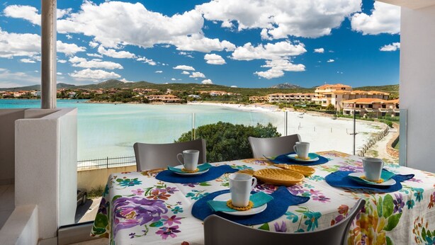 A balcony table with a view of a beach and buildings. - AIRONI - AIRONI 8 MONO (Golfo Aranci)