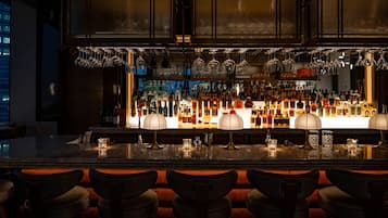 Een bar met verschillende zitmogelijkheden, een goed gevulde bar en hangend glaswerk.