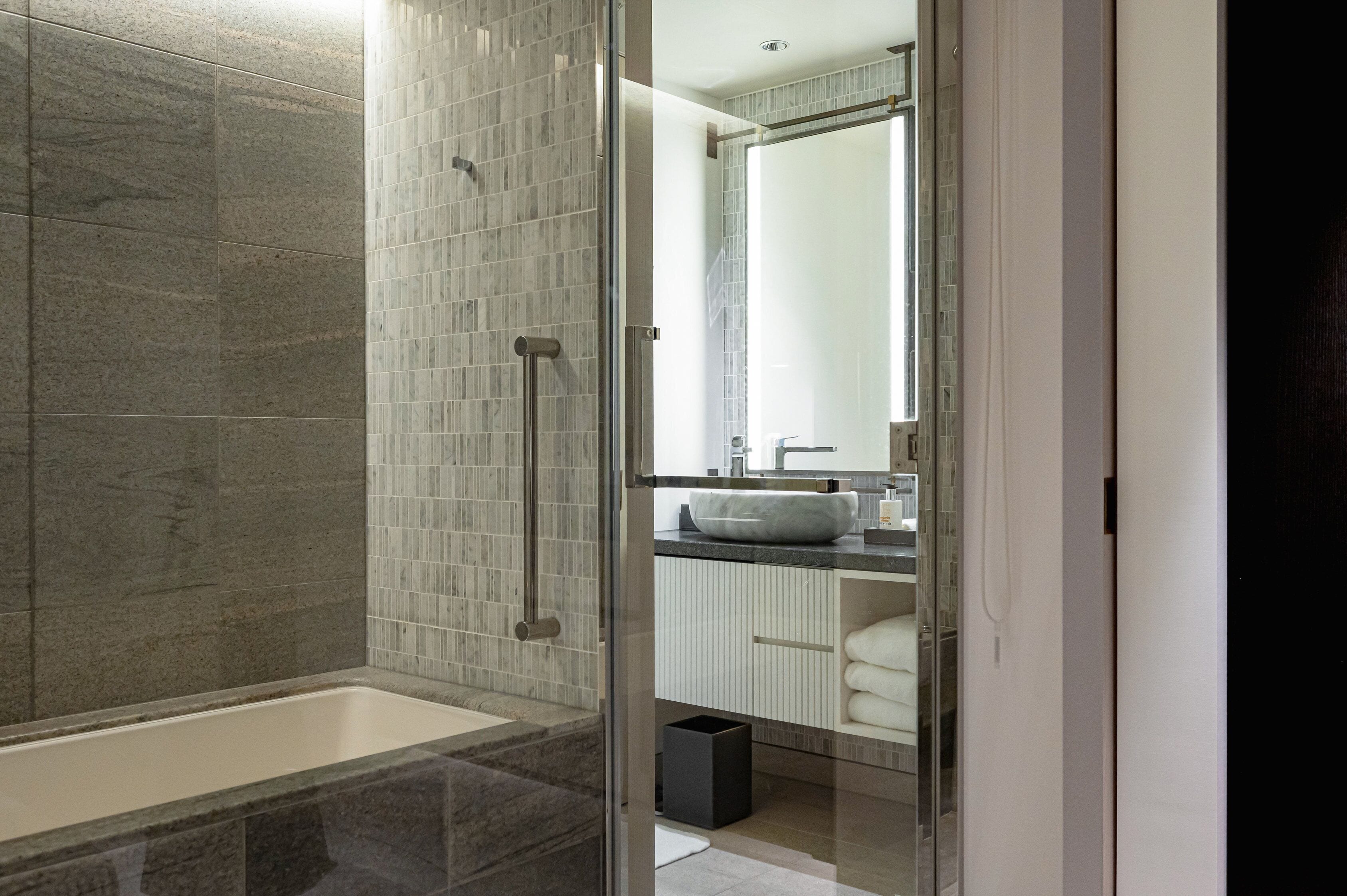 A modern bathroom with a glass-enclosed shower, a white sink, and a mirror above the sink.