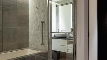 A modern bathroom with a glass-enclosed shower, a white sink, and a mirror above the sink.