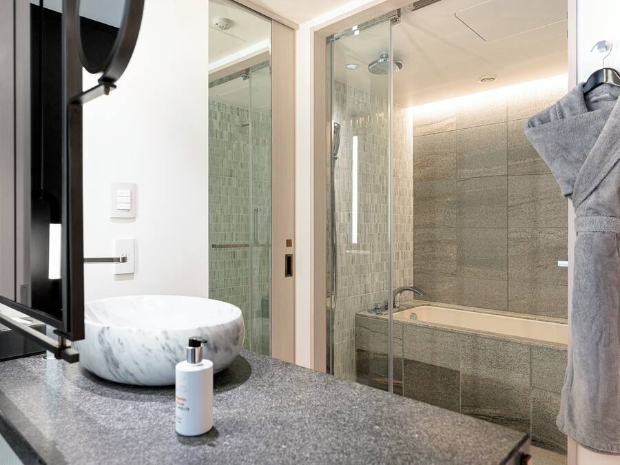 Ein modernes Badezimmer mit Marmorwaschbecken, einer Duschkabine aus Glas und einem Handtuchhalter.